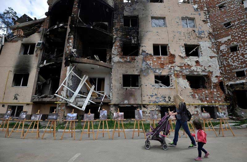 UNICEF hilft Ihnen: Mutter und Kind vor den Ruinen eines Wohnhaus in der Ukraine