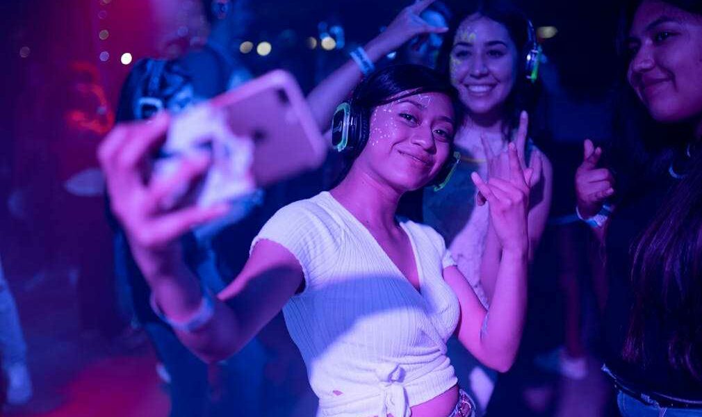 Jugendliche Frauen mit Selfie und Kopfhörer auf einer Teenie-Party