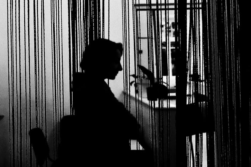 Ein Mensch sitzt hinter einem Vorhang im Schatten. Das Bild symbolisiert psychische Erkrankungen